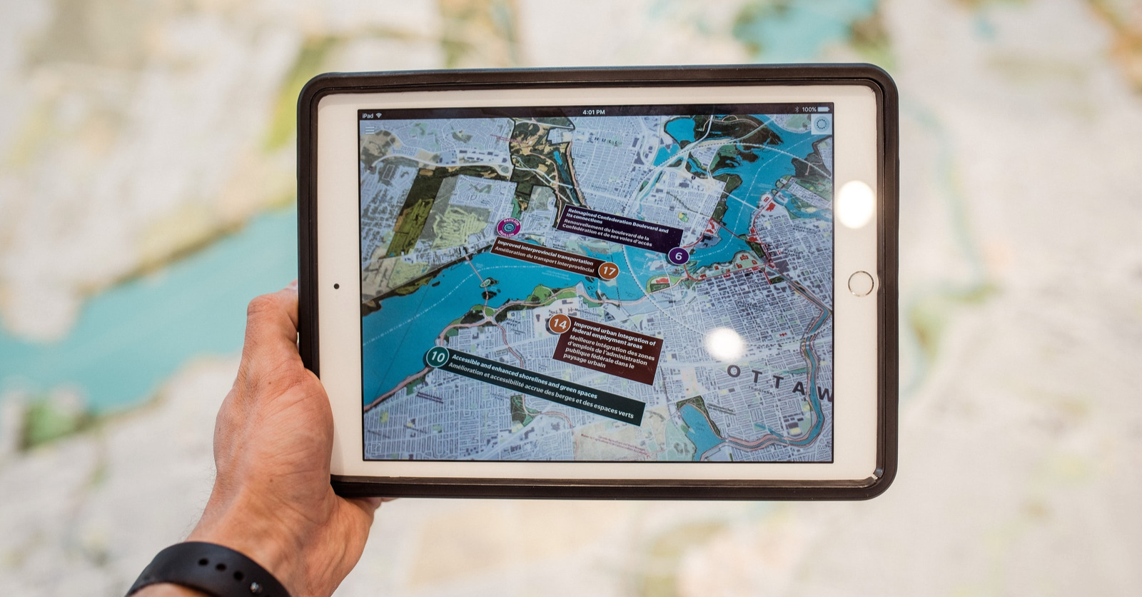 Eine Hand hält ein Tablet über eine Landkarte. Auf dem Tablet sind weitere Informationen zum angezeigten Kartenausschnitt eingeblendet.