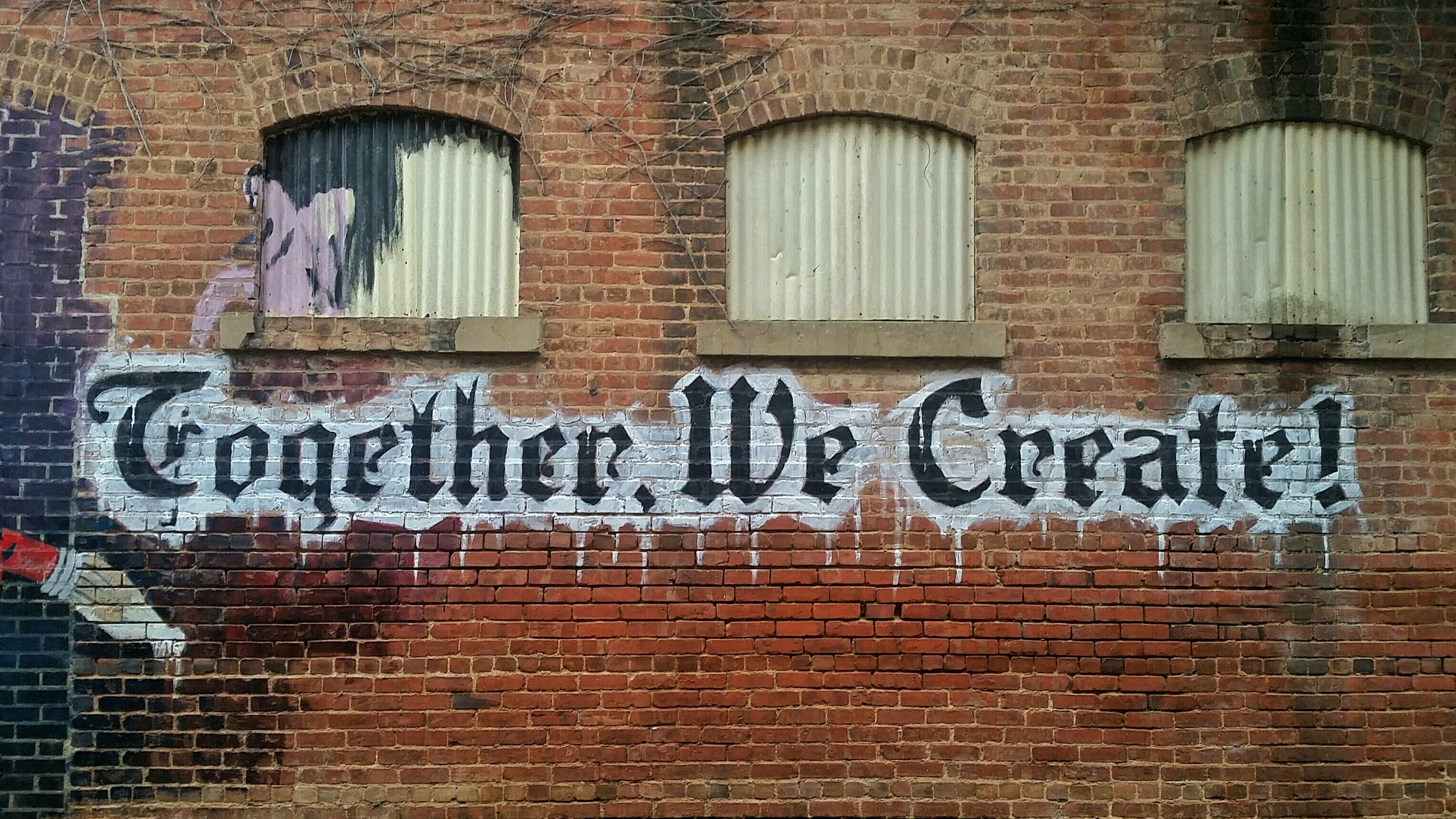 Graffiti-Schriftzug auf Backsteinmauer: Together, we create!